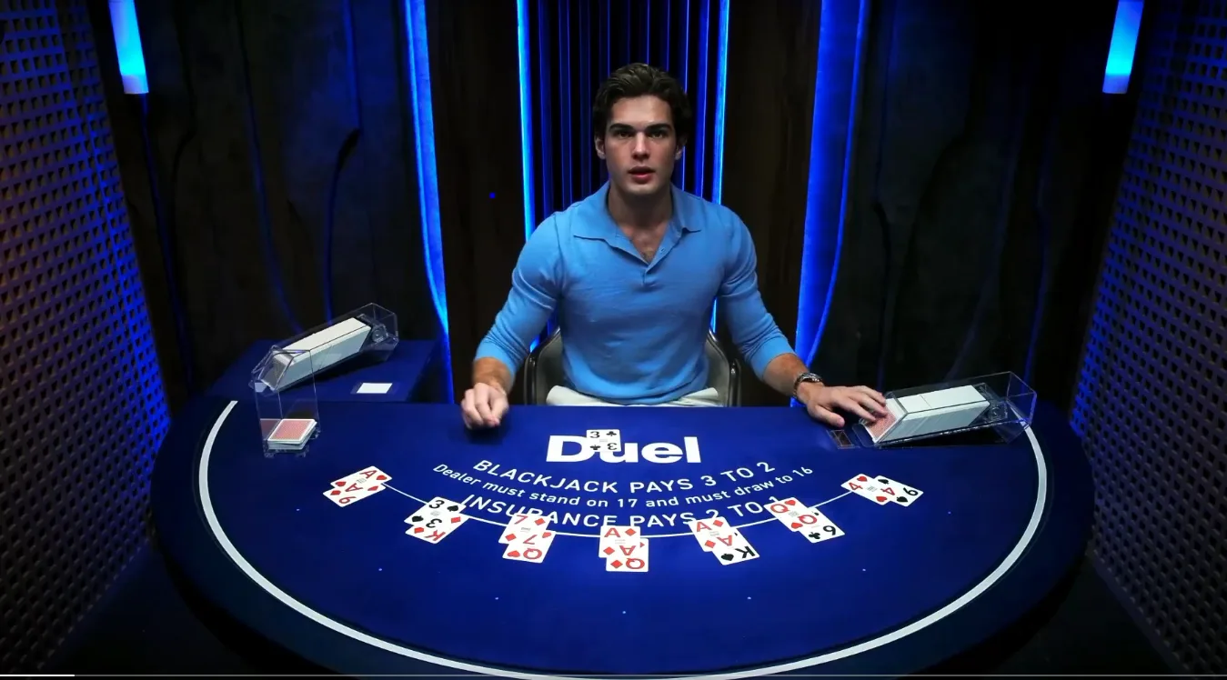 The Duel live blackjack table with a dealer, the rules on the felt and a hand dealt out